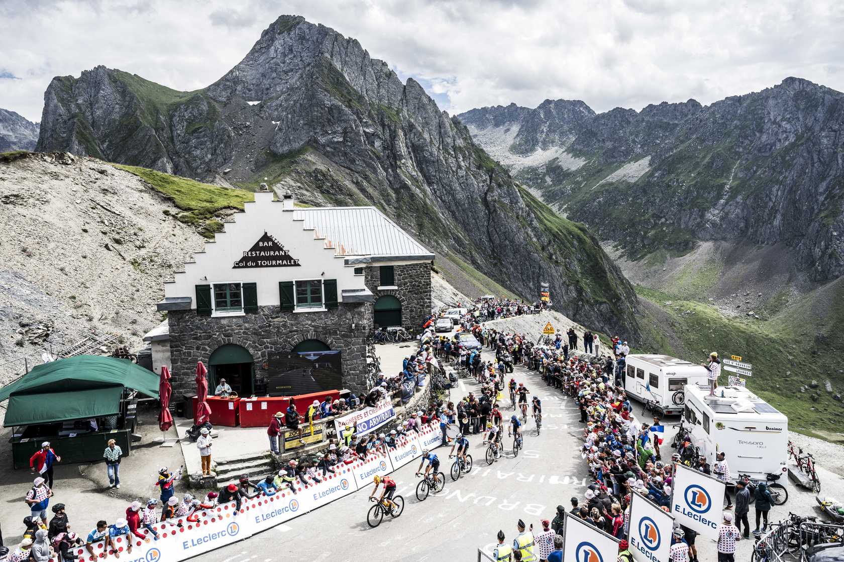 Cyclists race past a mountain refuge as large crowds of Dutch and Flemish fans cheer along the roadside.
